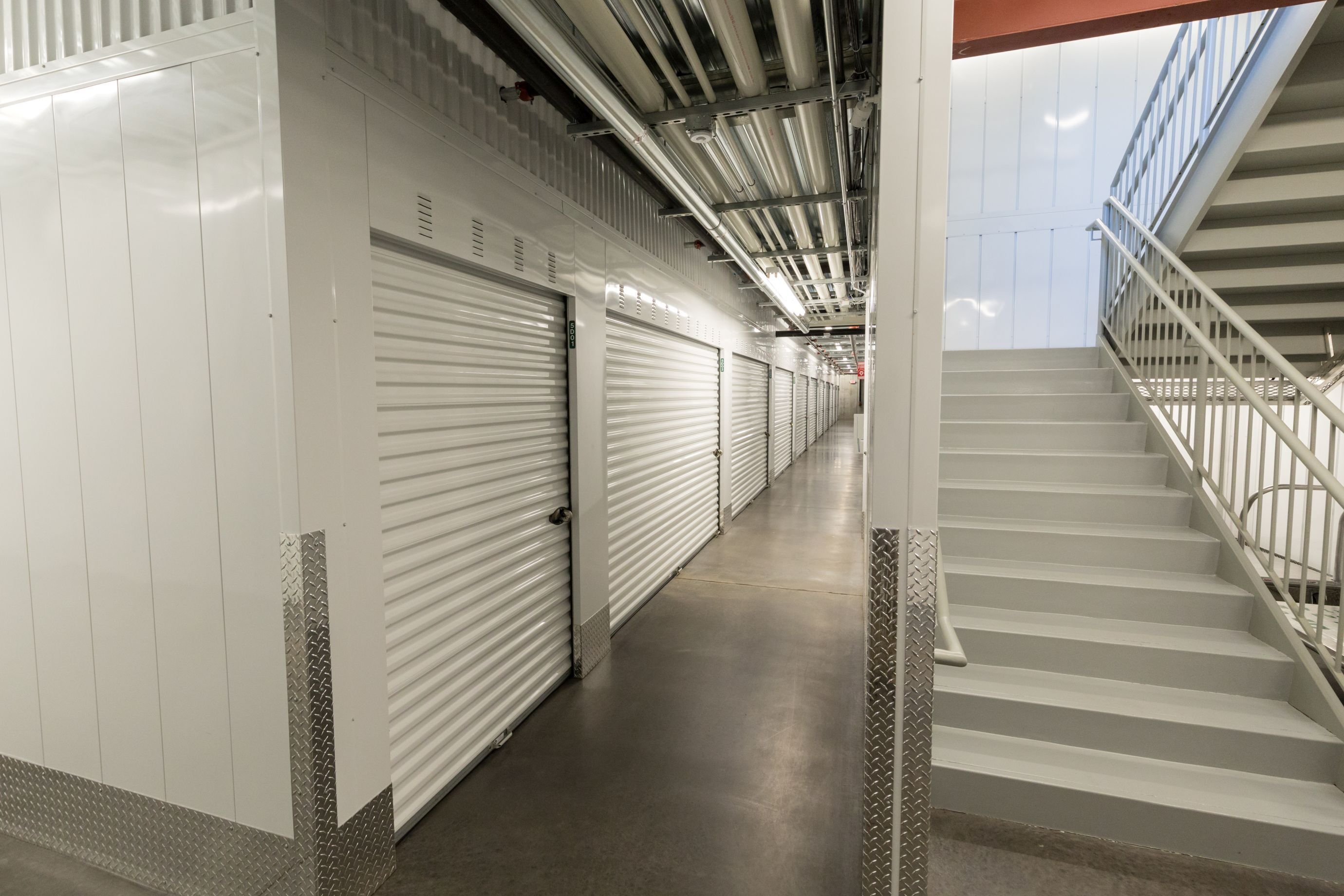Interior hallway at Lakes Region Storage with individual storage unit doors and upper-level access stairs, constructed by Rice Companies.