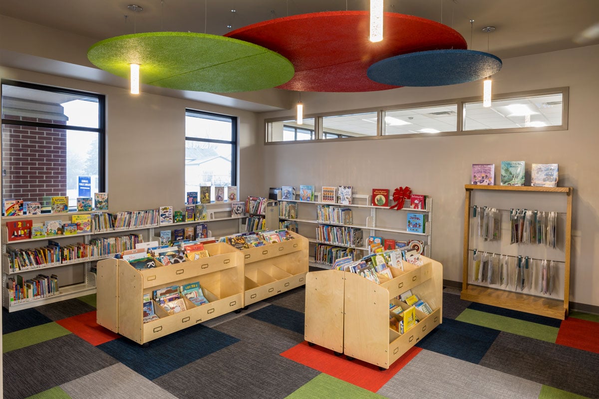 Children’s reading area inside Kimball Public Library with colorful ceiling panels and low book shelving, constructed by Rice Companies.