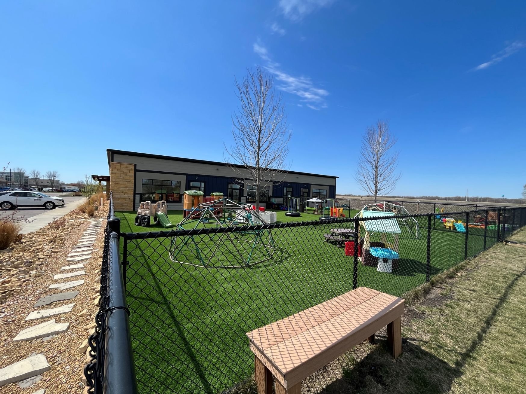 Outdoor play area at Jr’s Academy with fenced turf space and playground equipment, constructed by Rice Companies.