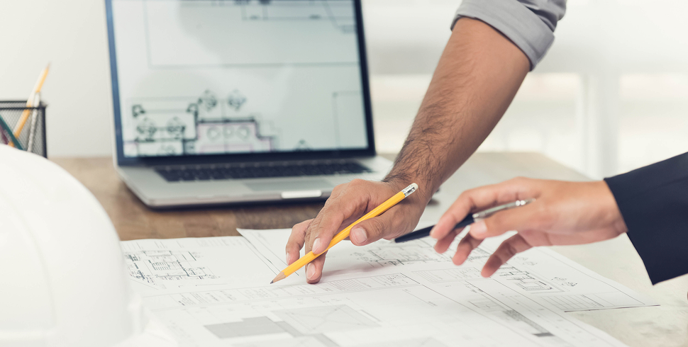 two-architects-reviewing-blueprints-with-pencil-and-laptop two-architects-reviewing-blueprints-with-pencil-and-laptop