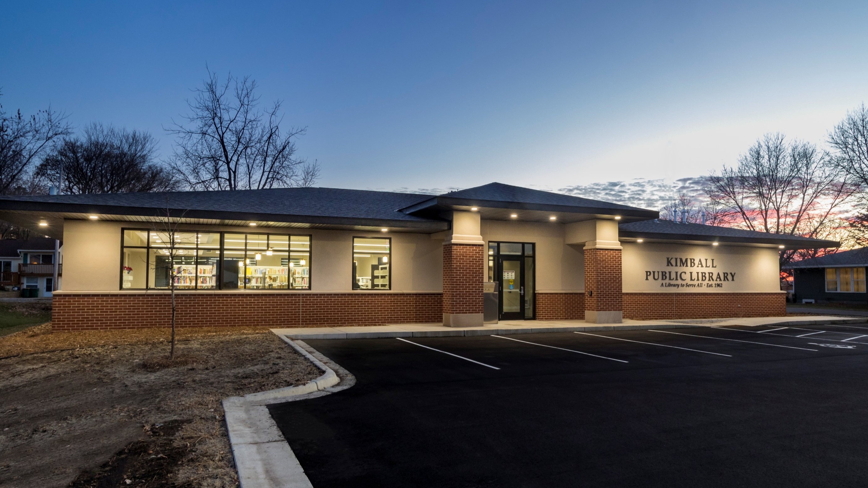 Kimball Public Library building exterior with illuminated entry and brick and stone detailing at dusk, constructed by Rice Companies.