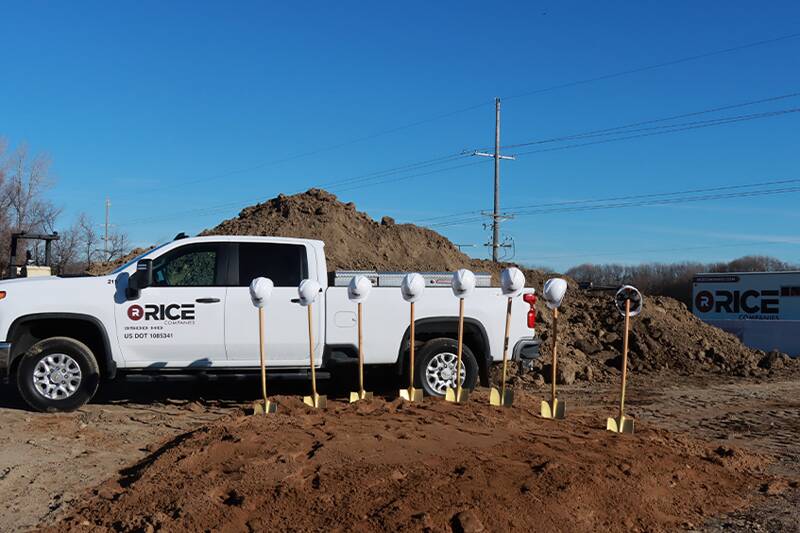 Work trucks with white hard hats on shovels