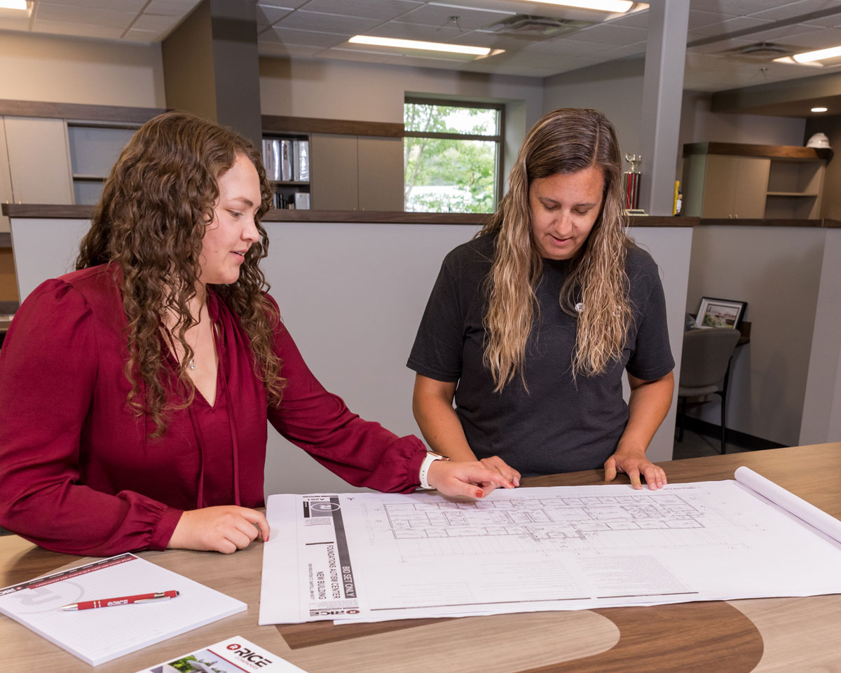 Women in office reviewing blue prints